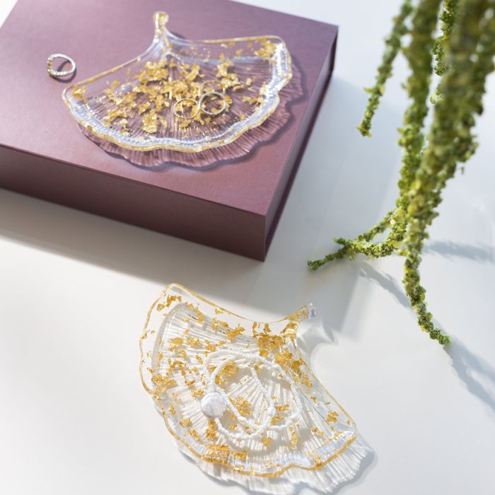 Kirkkaasta biohartsista valettu lehden muotoinen lautanen, jossa kullanvärisiä yksityiskohtia